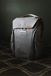 gray leather backpack on brown and white floral textile