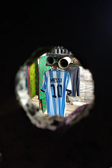A dynamic shot of a Manchester City home jersey hanging against a soft blue background.