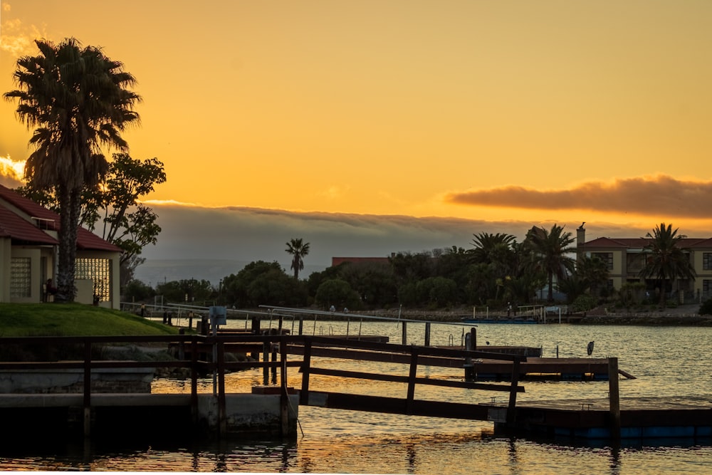 brown wooden dock on lake during sunset