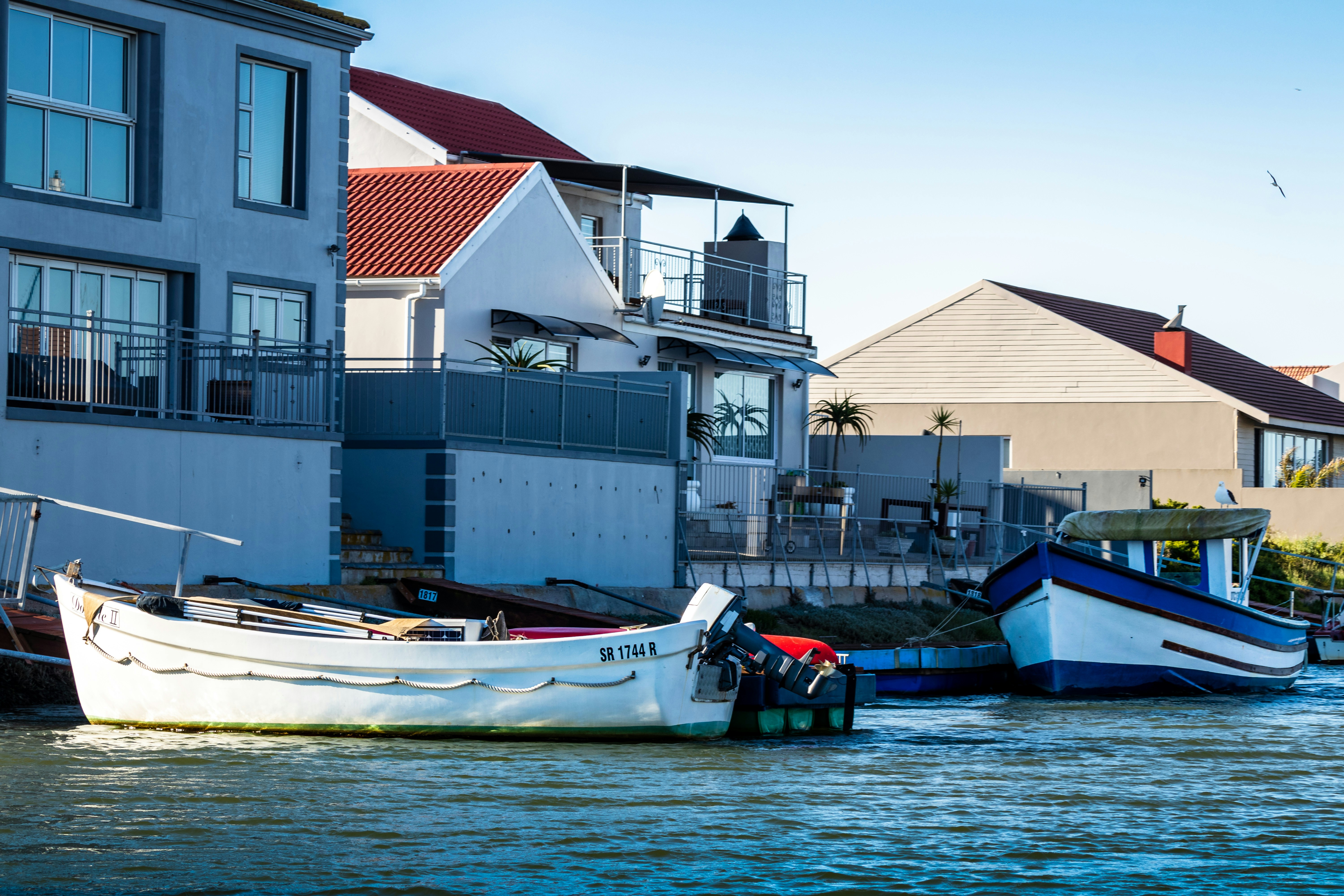 white and blue boat on water near white concrete building during daytime