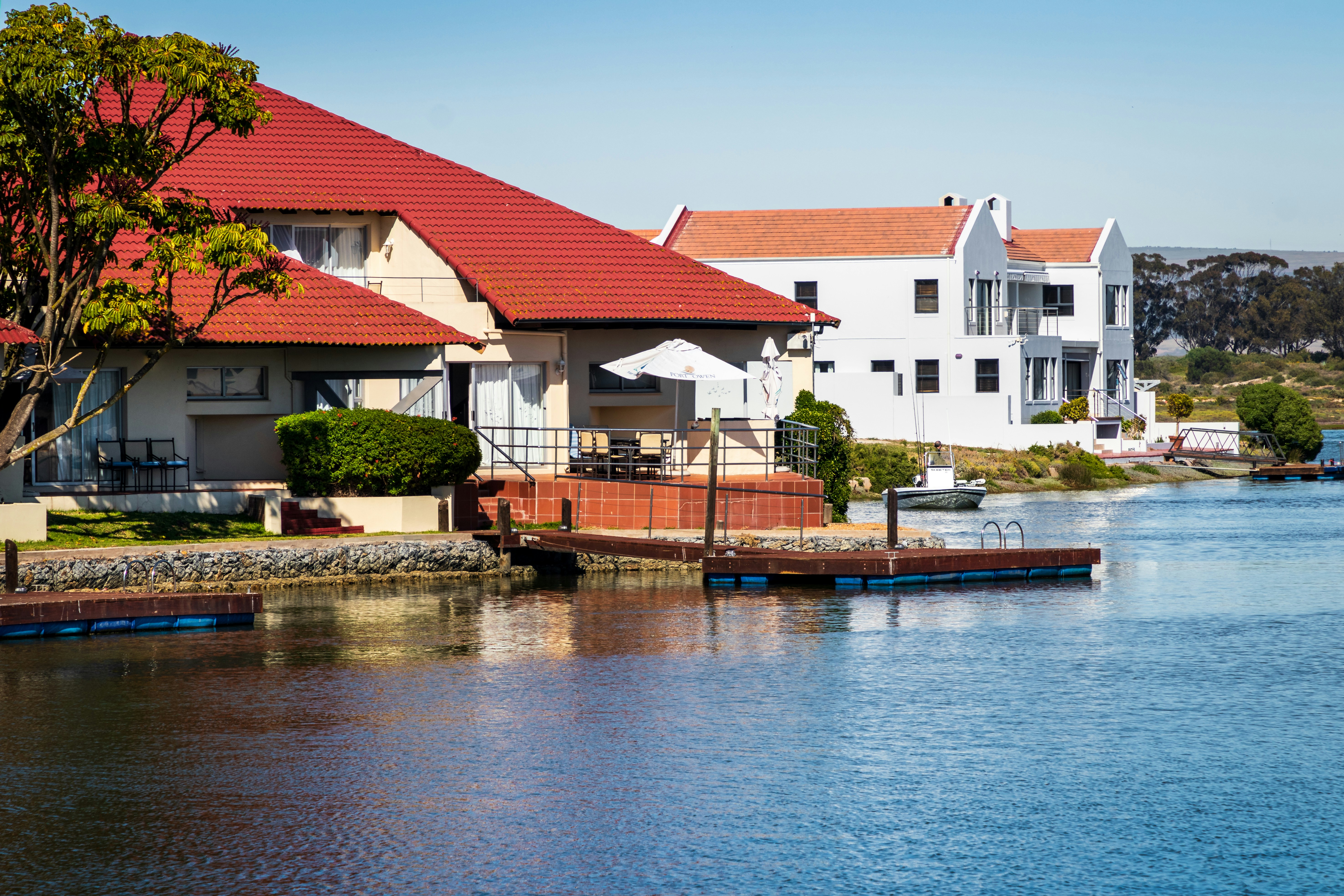 Maisons en béton blanc et rouge au bord de la rivière sous le ciel bleu pendant la journée