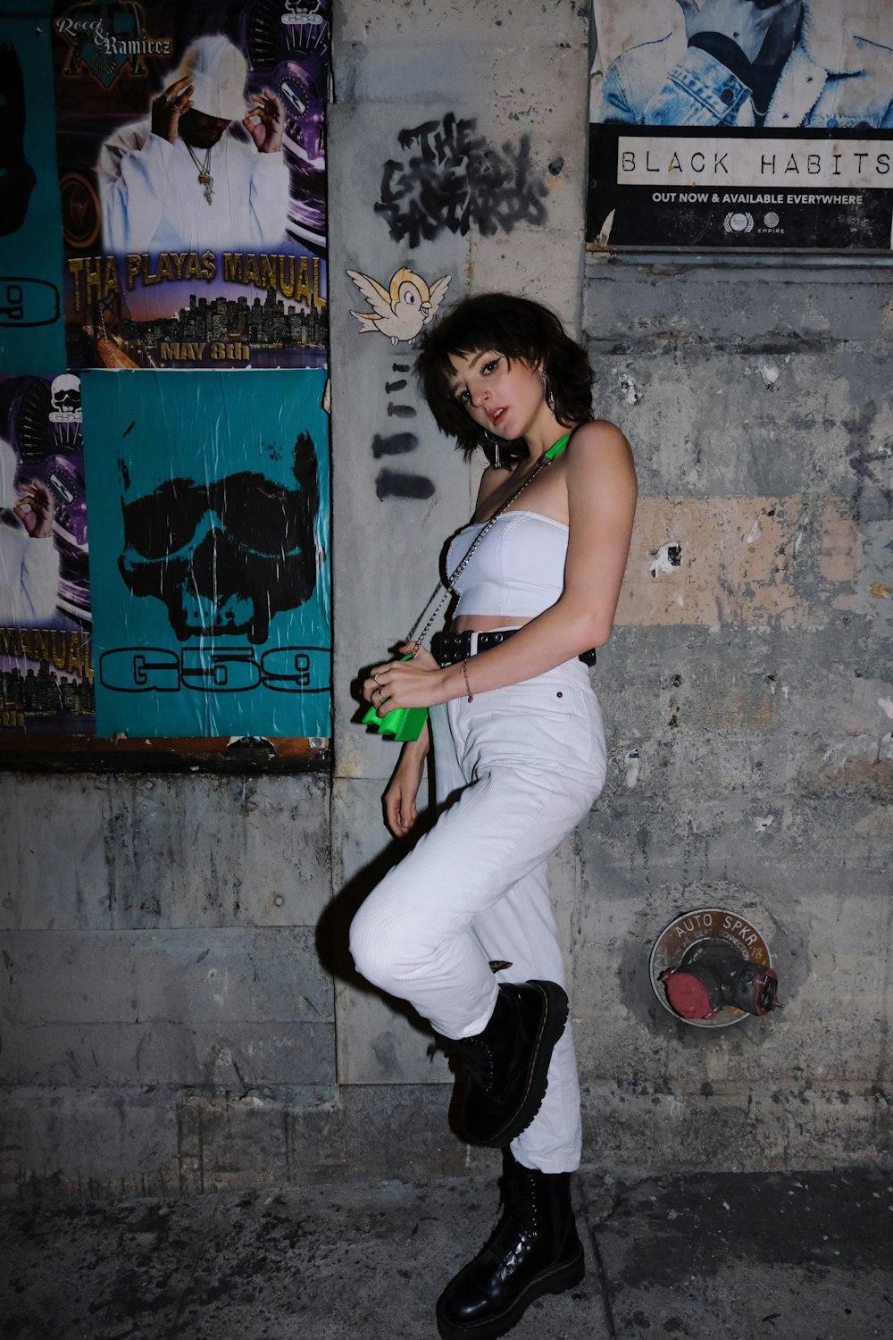 woman in white tank top and white pants holding black dslr camera