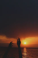 Sunset silhouette of worshippers raising hands in praise on the church lawn.