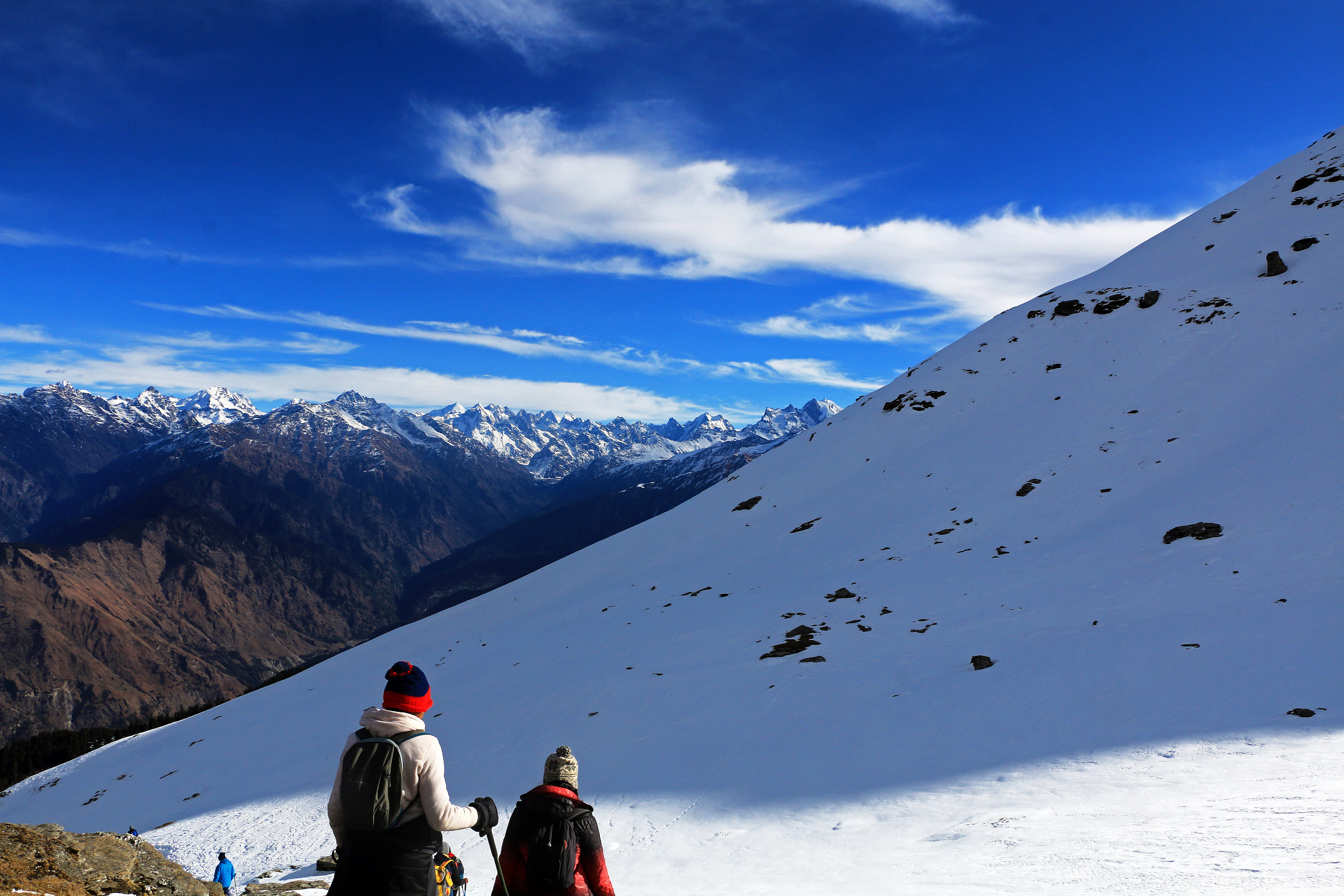Trekkers with backpacks on a snowy slope below Kedarkantha peak, Uttarakhand