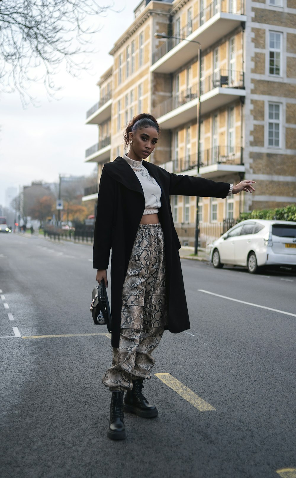 man in black blazer and brown and white floral pants standing on road during daytime