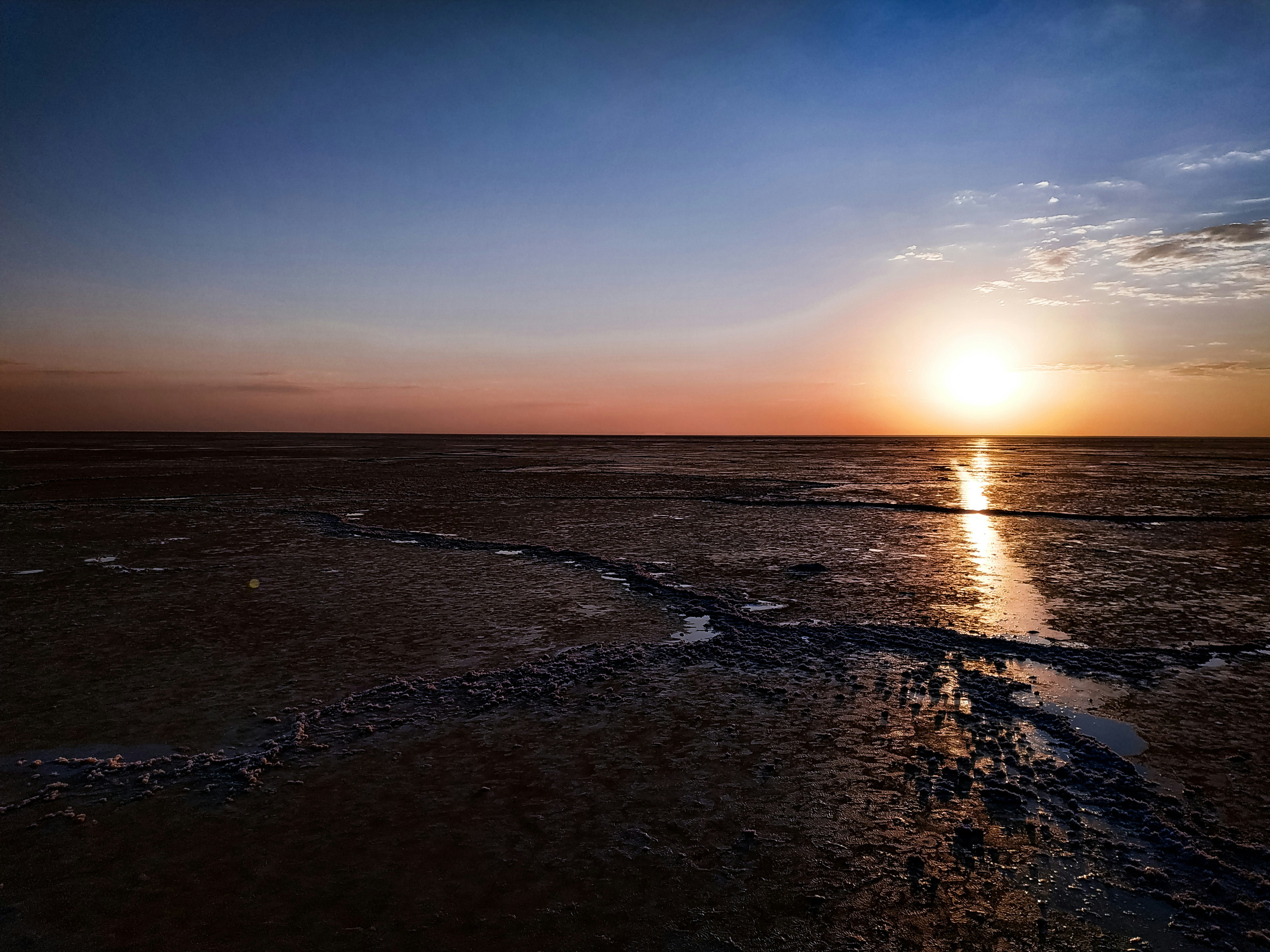 the sun is setting over the water on the beach