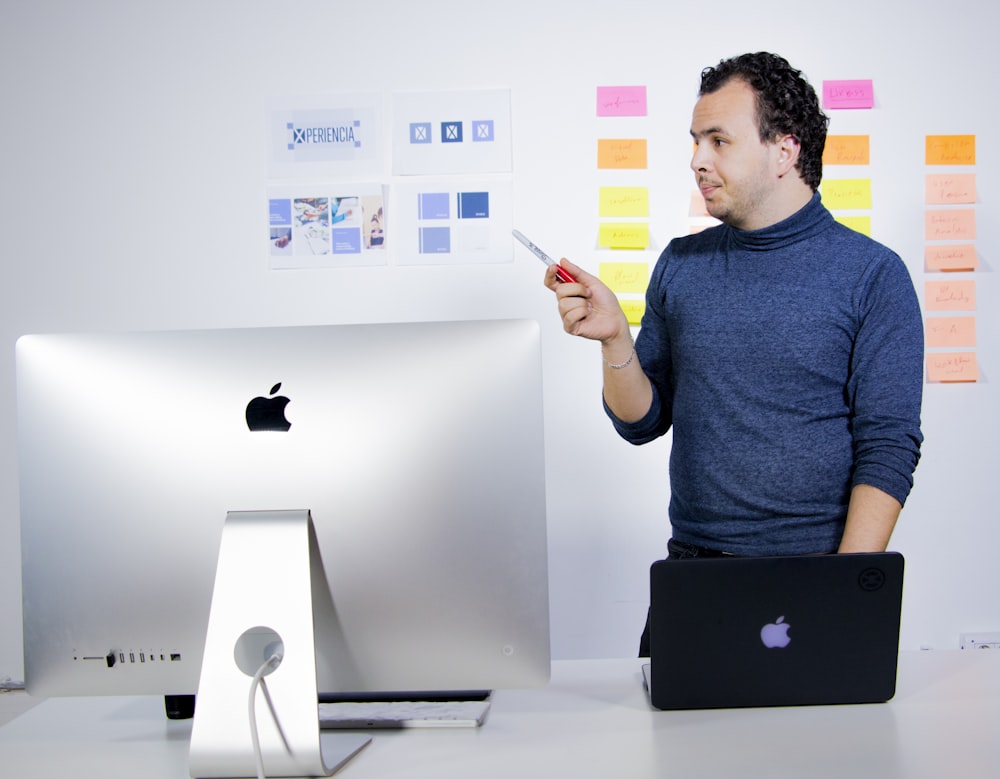 man in blue crew neck t-shirt holding black laptop computer