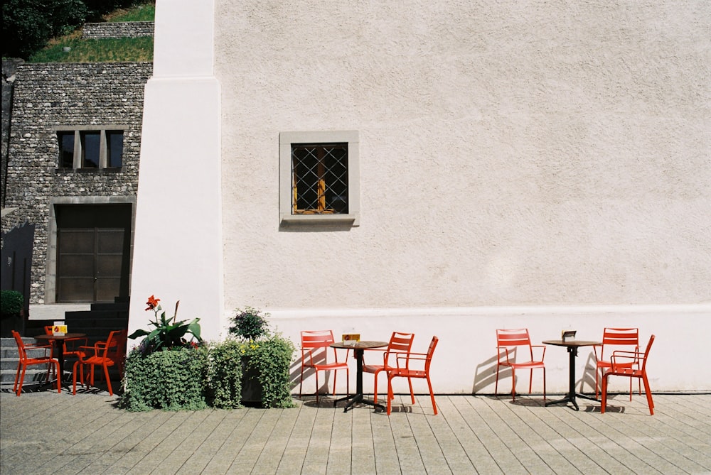 red and brown wooden chairs and table near white concrete wall