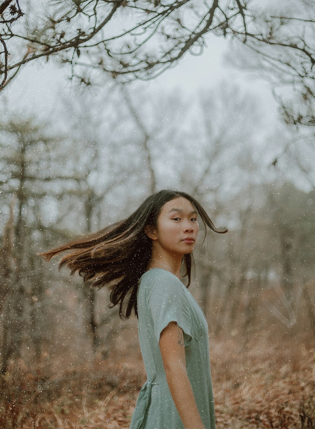 woman in gray long sleeve shirt standing near white leaf trees during daytime