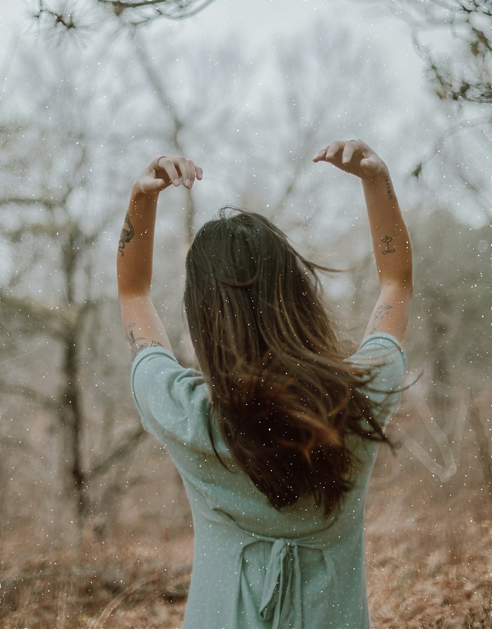 woman in teal long sleeve shirt raising her hands