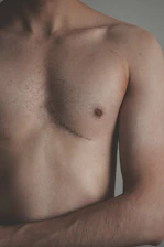 topless man standing near white wall
