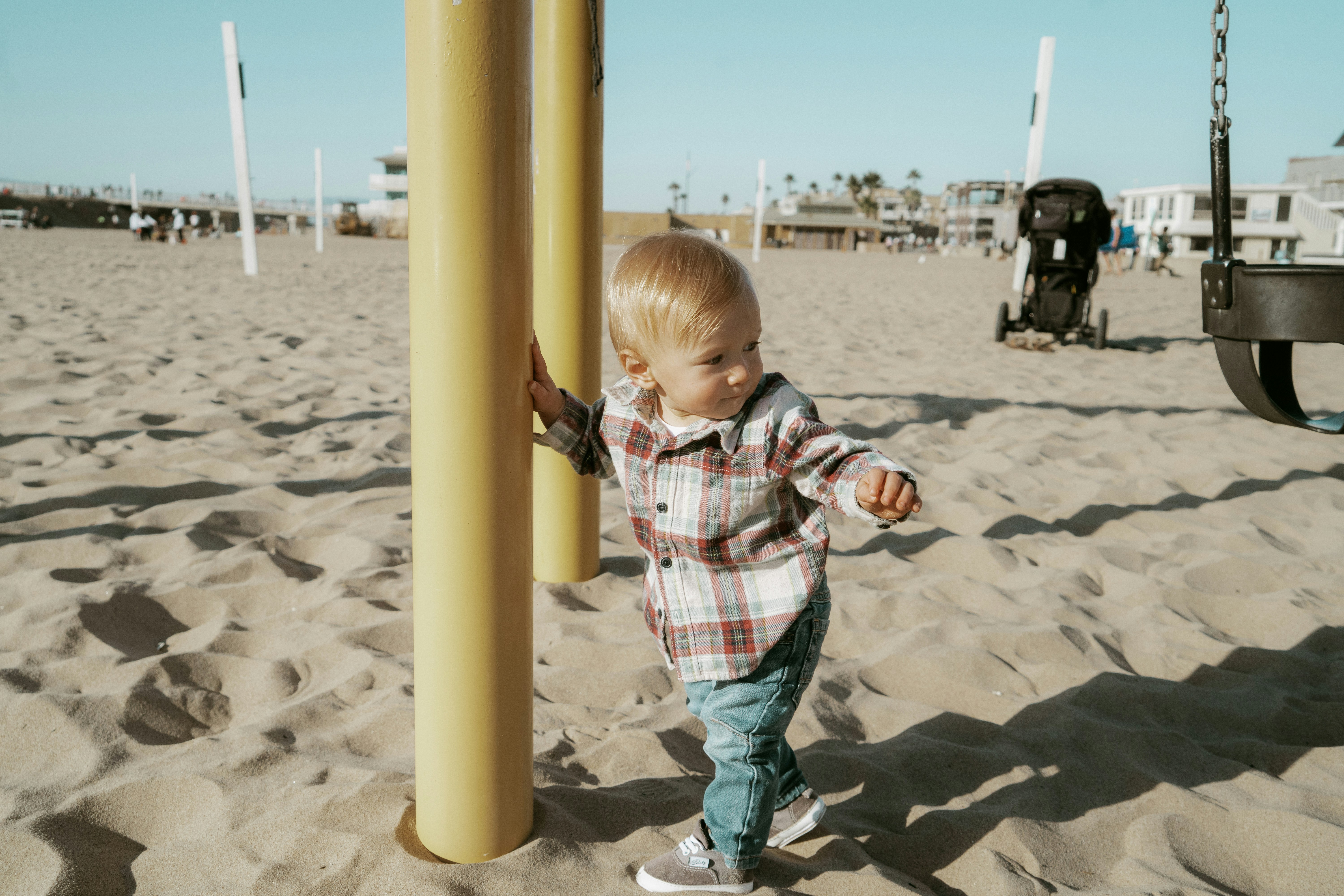 boy in red white and blue plaid button up shirt standing on beach sand during daytime
