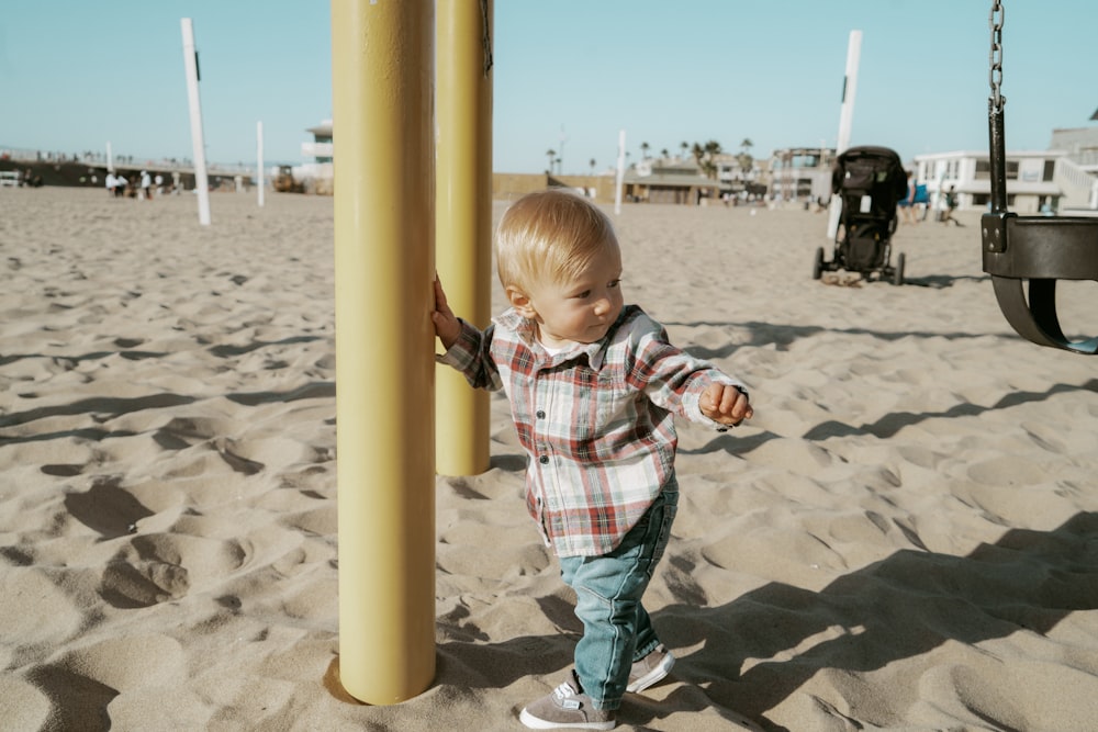 boy in red white and blue plaid button up shirt standing on beach sand during daytime