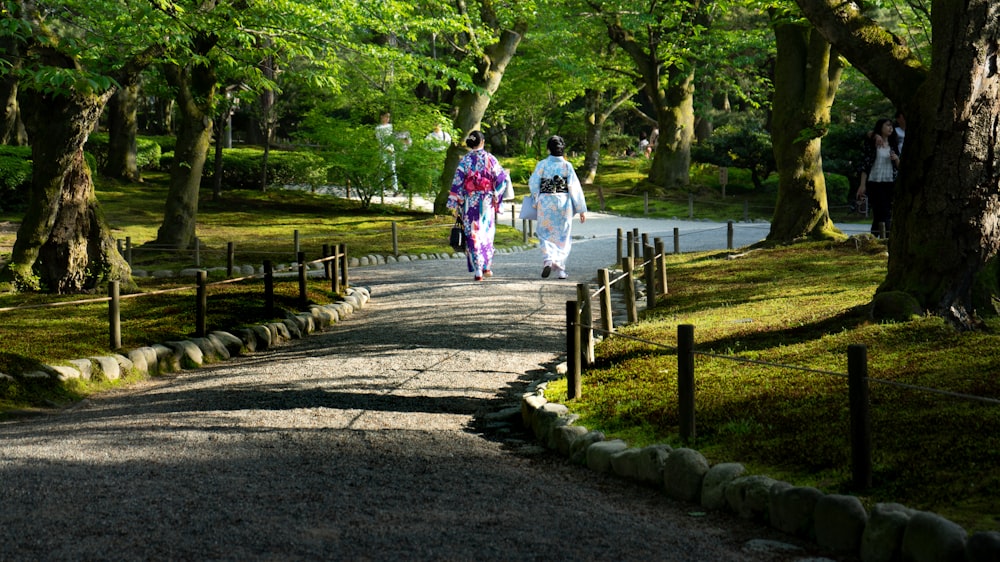 2 women standing on brown wooden fence near green trees during daytime