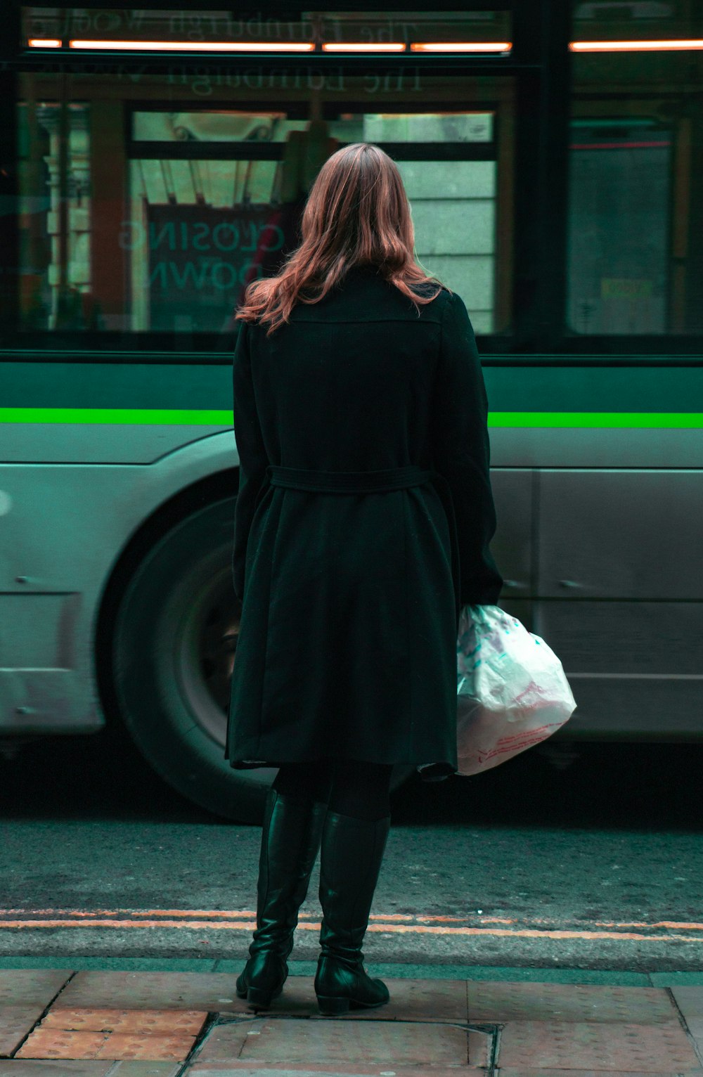 woman in black coat standing on sidewalk during daytime