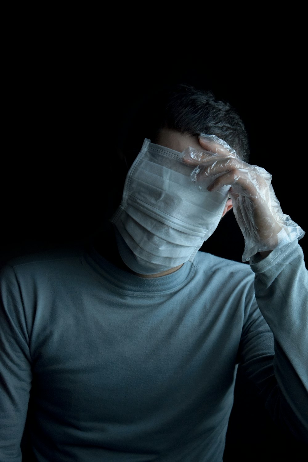 uomo in camicia grigia a maniche lunghe girocollo che copre il suo viso