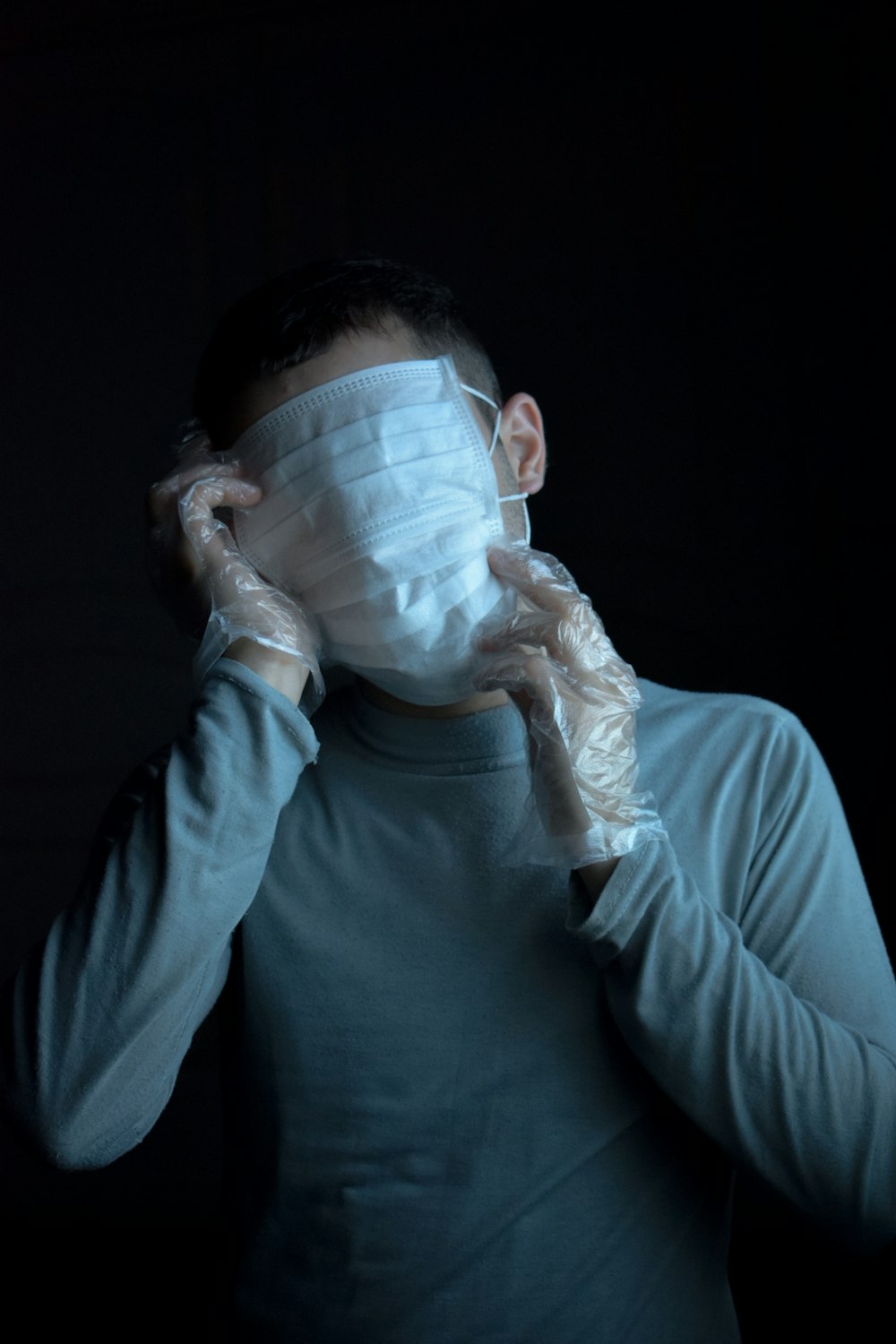 mulher na camisa cinzenta da gola rolê da manga comprida que cobre o rosto com saco plástico branco