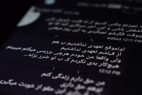 The image displays text on a digital screen with black background. The text is written in Persian and white font. The time 12:11 PM and an indication of editing are visible.