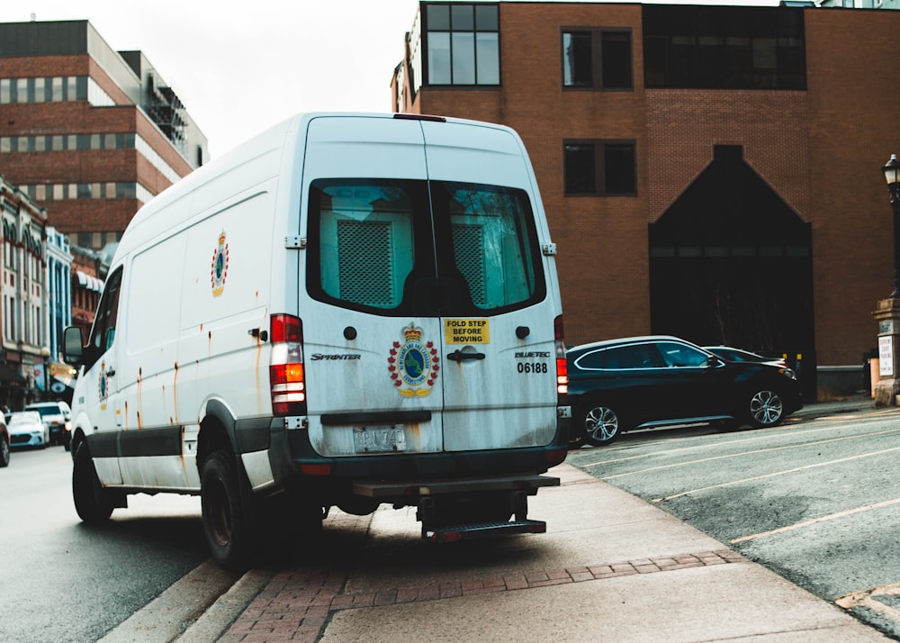 white van parked on sidewalk during daytime