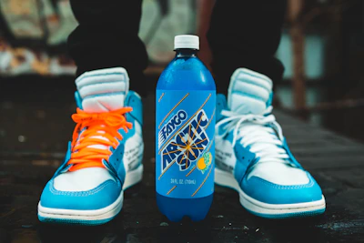 Casual day shoes paired with a playful bottle on a city sidewalk.