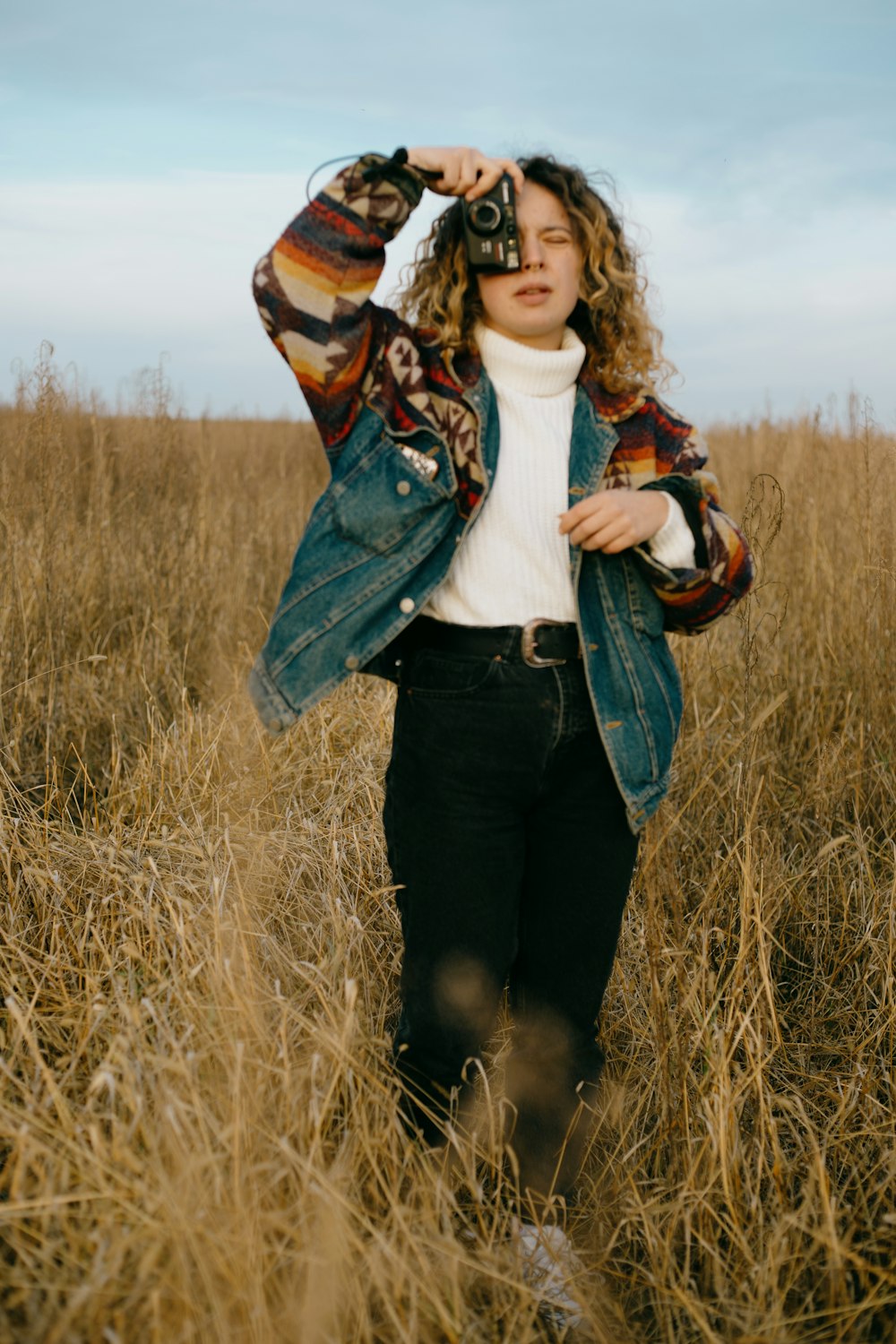 woman in white shirt and green jacket standing on brown grass field during daytime