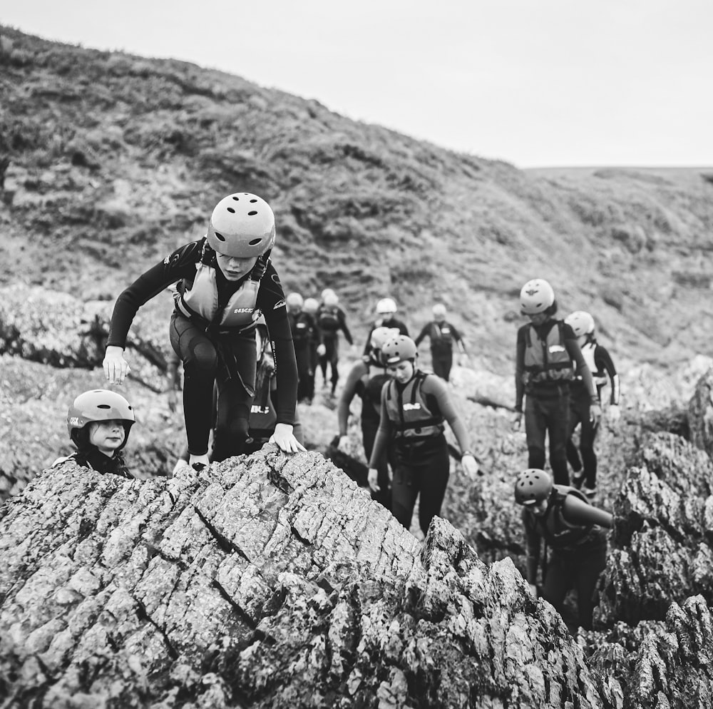 grayscale photo of people on rock formation