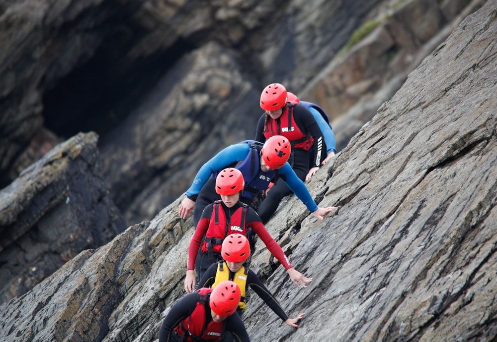 2 women in red and blue suit climbing on brown rock