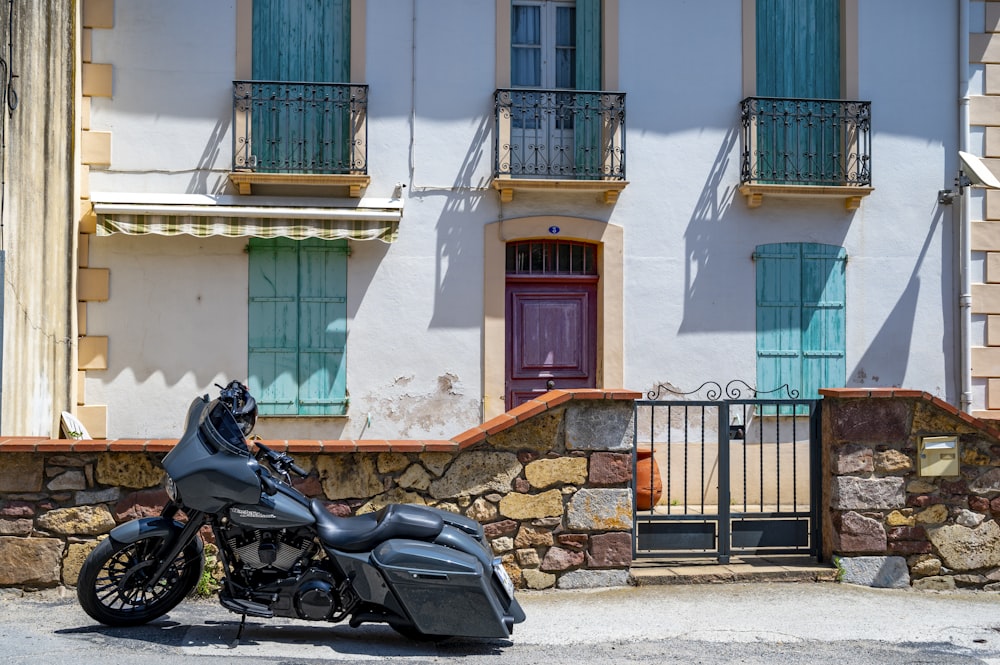black motorcycle parked beside blue and pink concrete building during daytime