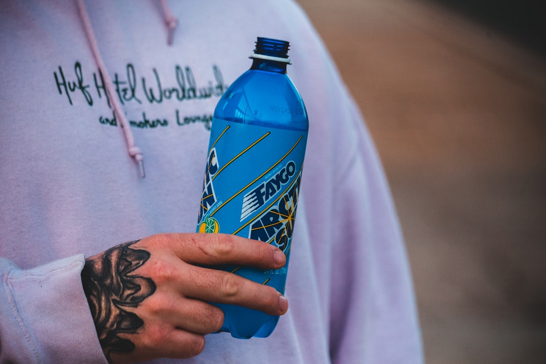 person holding blue and yellow plastic bottle