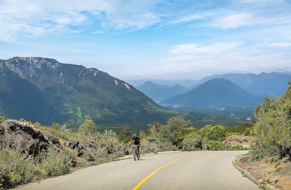 man in black jacket and black pants riding bicycle on road during daytime