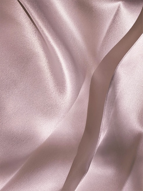Soft, luxurious silk fabric draped gracefully, showcasing its smooth texture and subtle sheen
