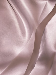 Soft, flowing fabric with a smooth, shiny texture featuring gentle folds and a subtle sheen, creating an elegant and luxurious appearance.