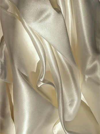 A richly textured espresso-colored fabric draped smoothly over a cream surface.