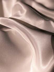 Smooth, lustrous fabric with natural folds reflecting light and creating a soft, luxurious sheen.