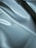 Smooth, shiny fabric with a silky texture featuring soft folds and a light reflection that adds depth and texture to the surface.