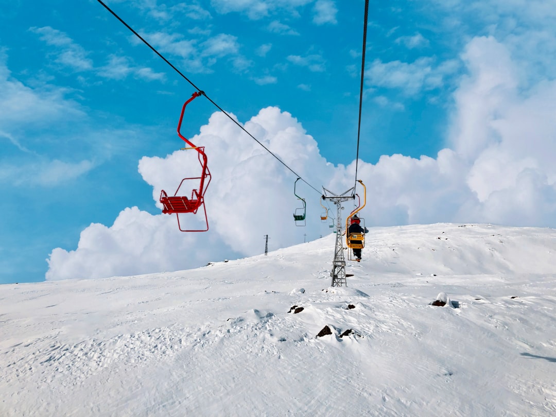 person in yellow jacket and black pants riding on cable car over snow covered ground during
