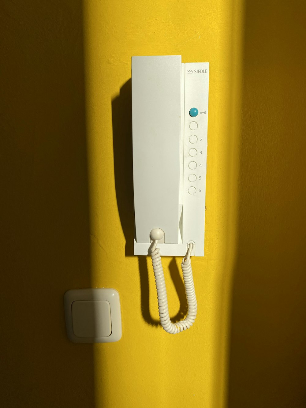 white wall mounted telephone on yellow wall
