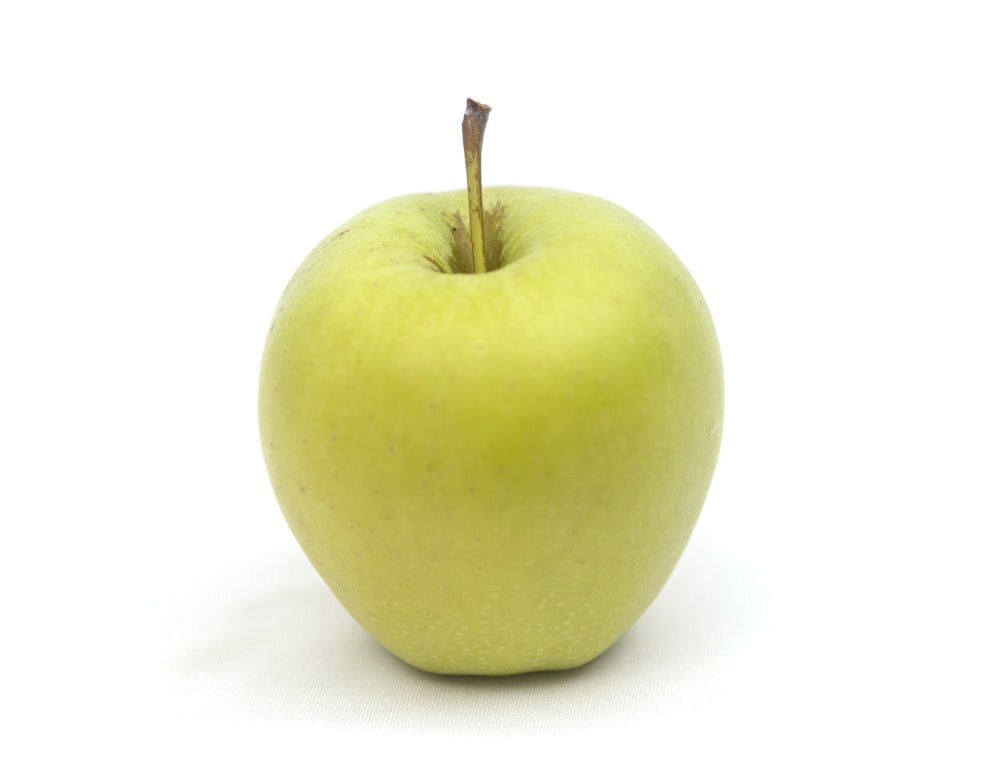 manzana verde sobre superficie blanca
