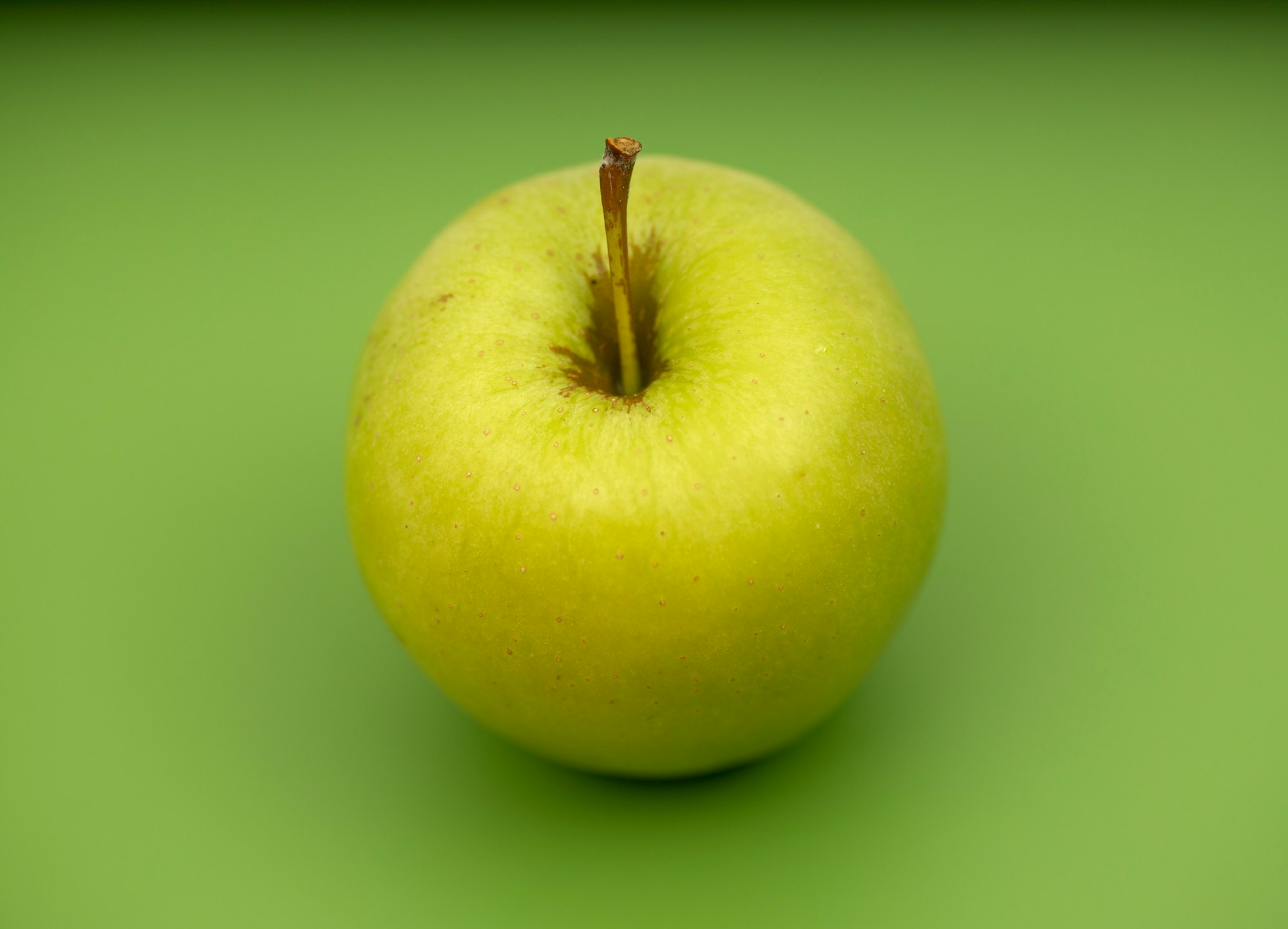 Yellow apple on green background