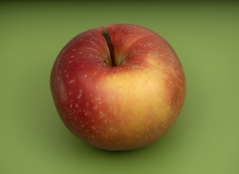frutto di mela rossa su superficie verde