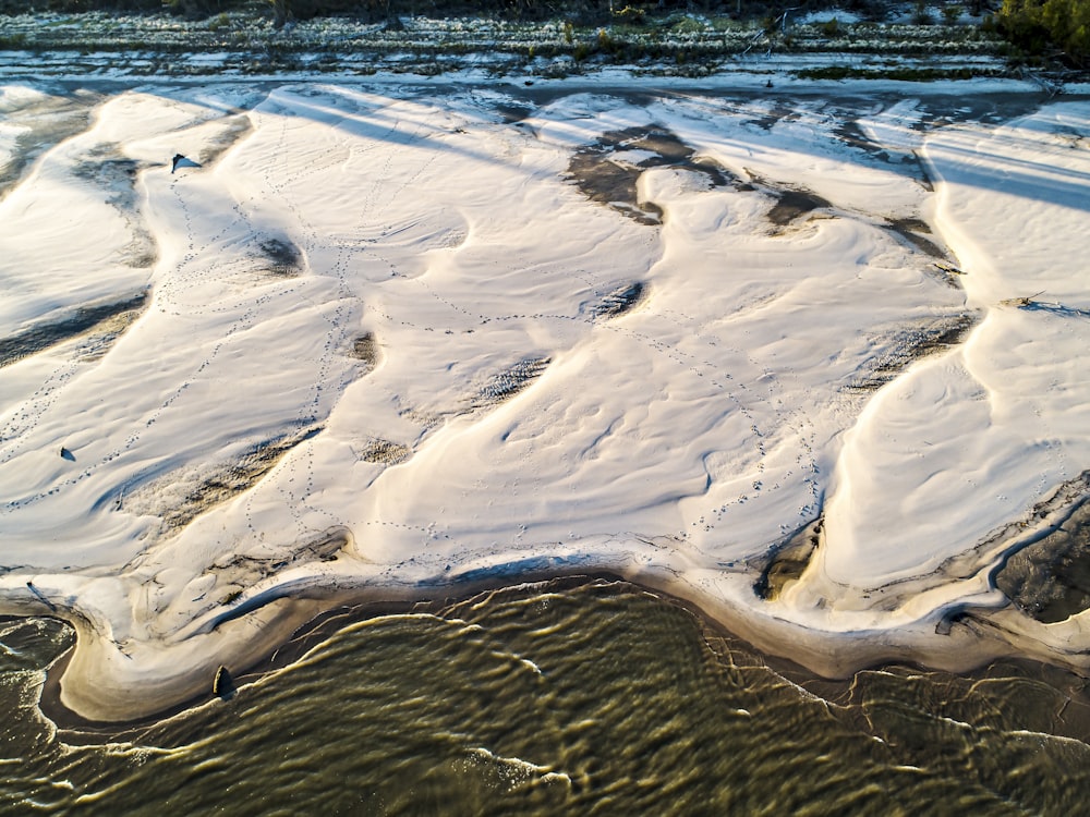 areia marrom perto do corpo de água durante o dia