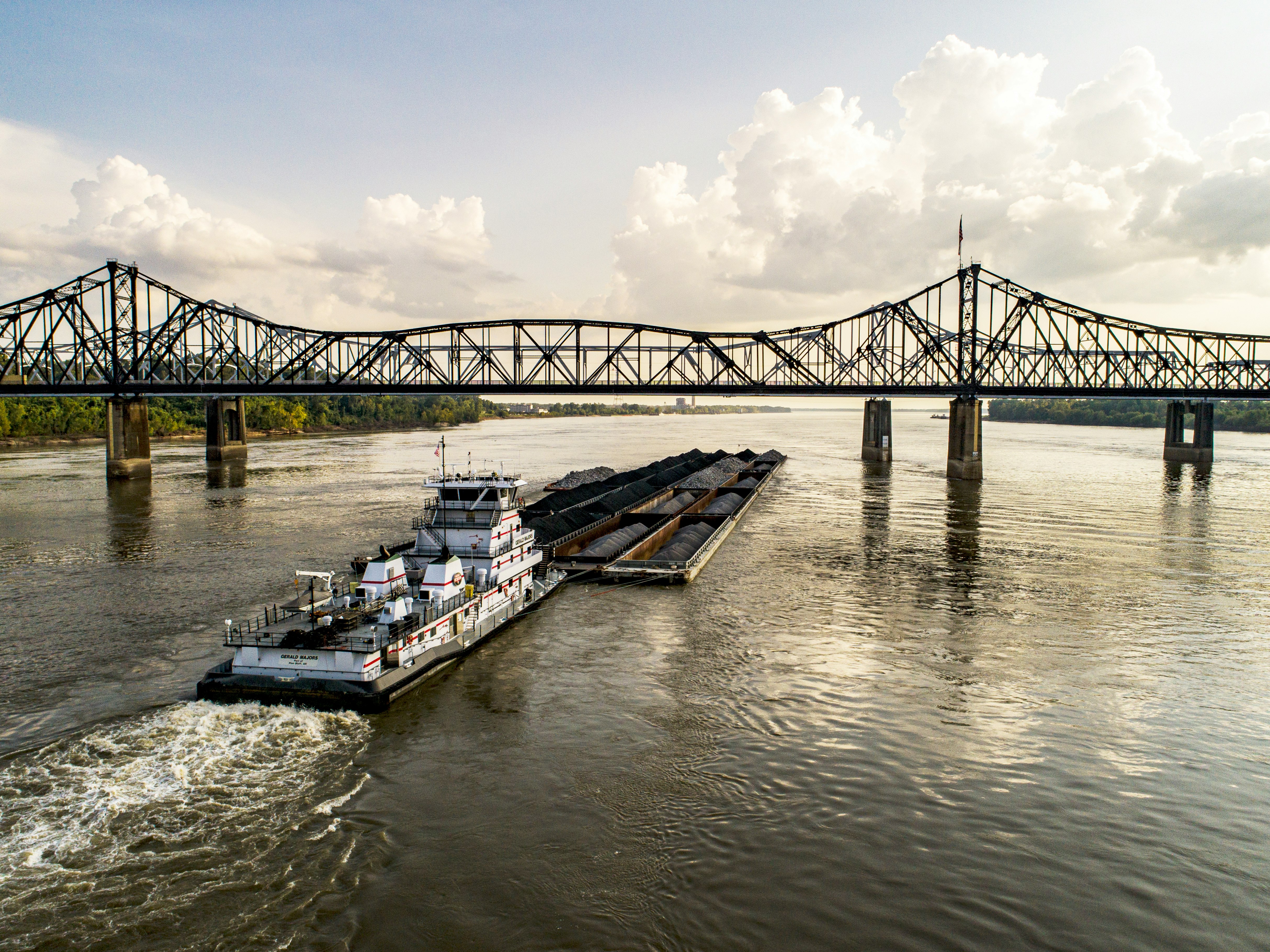 Headed down the Mississippi River, a tugboat pushes barges as it passes under the Vicksburg Bridge.