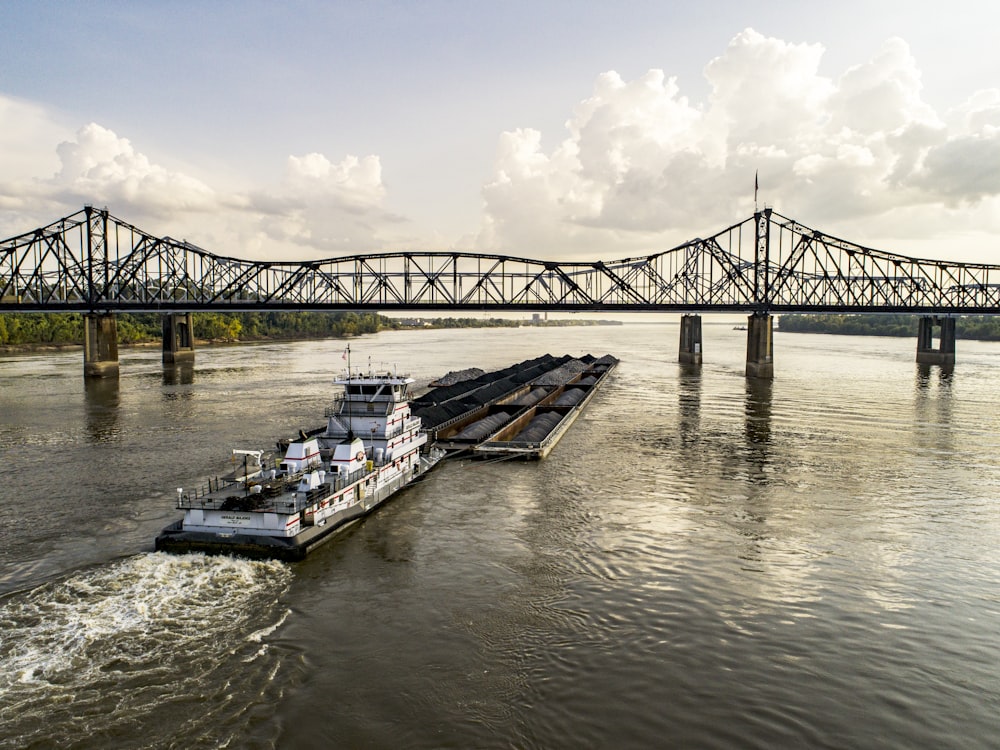 Bateau blanc et bleu sur la mer sous le pont pendant la journée