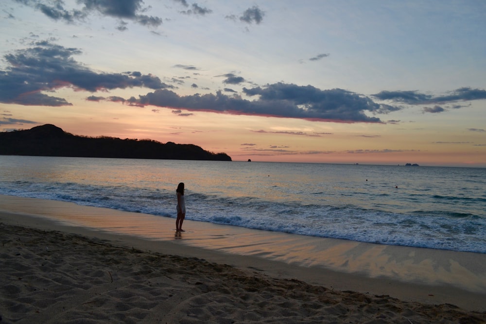 woman in black bikini walking on beach during sunset