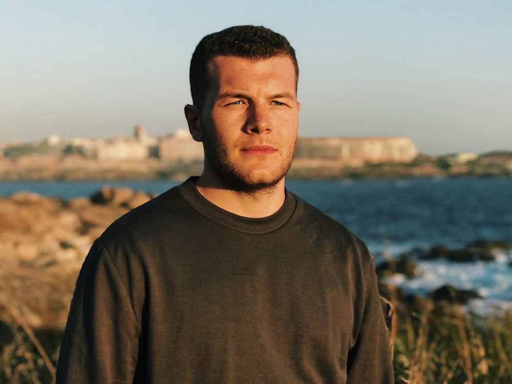 man in gray crew neck shirt standing near body of water during daytime