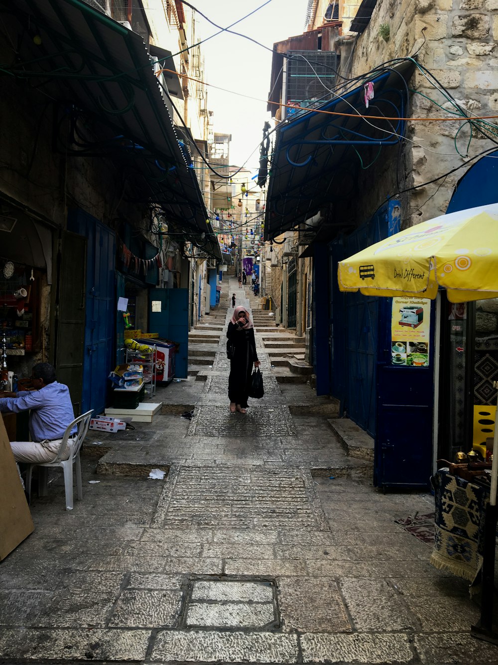 woman in black jacket walking on sidewalk during daytime