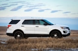 white suv on brown grass field under white clouds during daytime