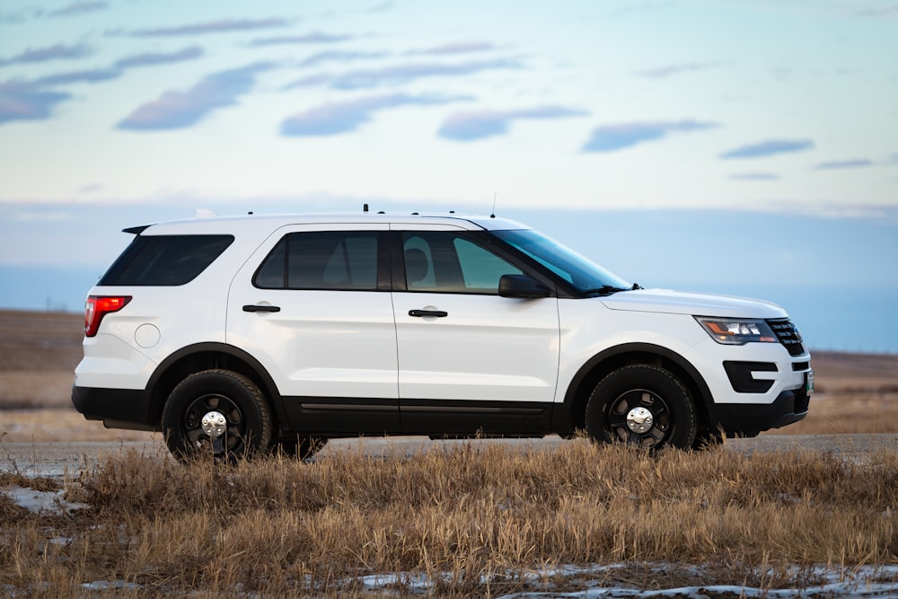 white suv on brown grass field under white clouds during daytime