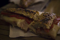 Quesocaliente sandwich melting cheese perfectly with fresh tomato and lettuce.