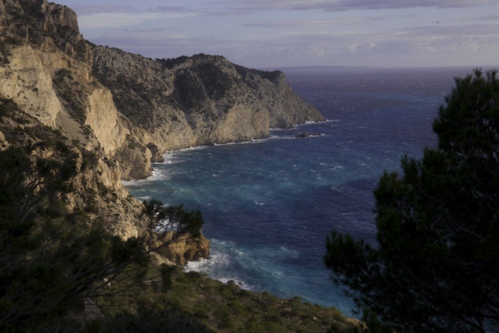 brown and green mountain beside blue sea under blue sky during daytime